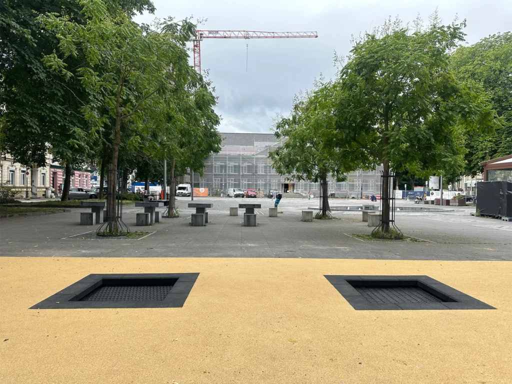 Barrierefreier Platz mit zwei eingebauten Bodentrampolinen auf hellem Fallschutzbelag in der Innenstadt von Stolberg, NRW – Teil des Wiederaufbaus nach dem Hochwasser 2021, um urbanen Raum familienfreundlich zu gestalten.