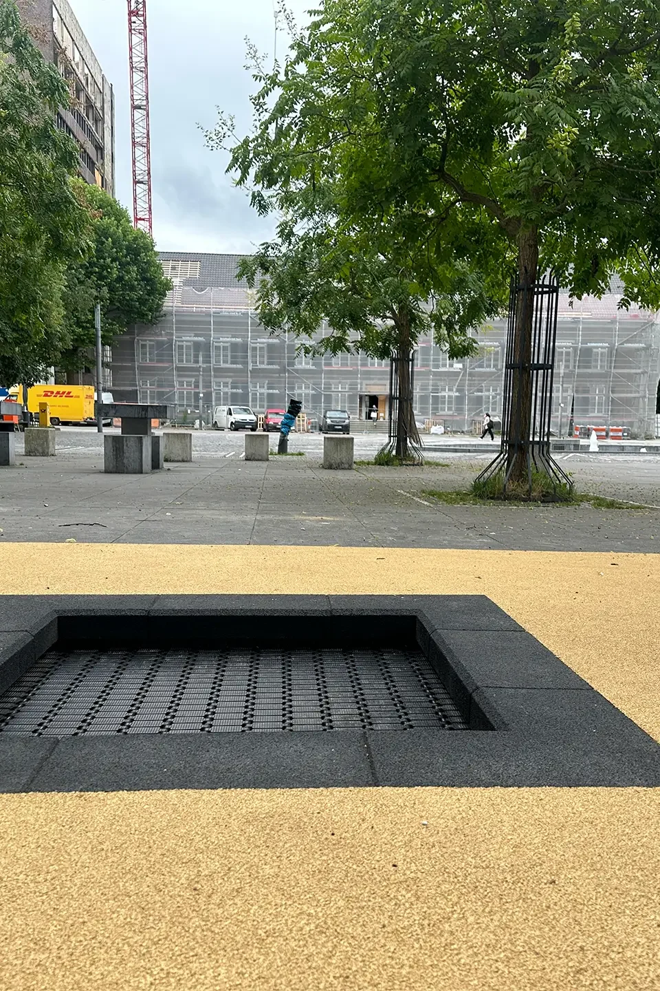 Barrierefreier Platz mit zwei eingebauten Bodentrampolinen auf hellem Fallschutzbelag in der Innenstadt von Stolberg, NRW – Teil des Wiederaufbaus nach dem Hochwasser 2021, um urbanen Raum familienfreundlich zu gestalten.