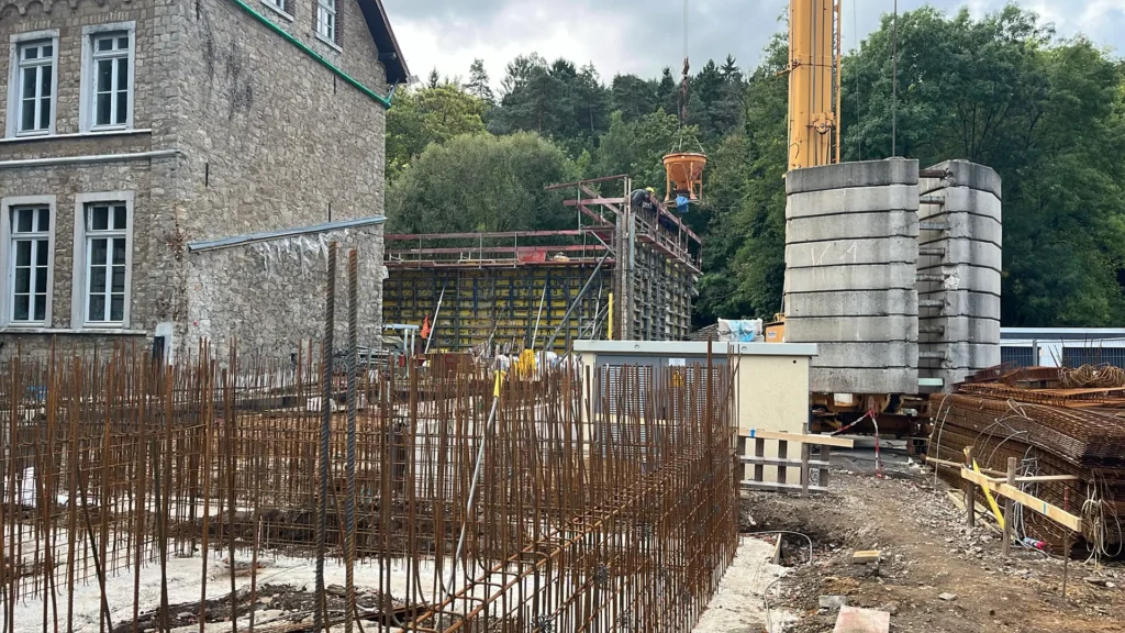 Baustelle mit Bewehrung und Kranarbeiten neben dem Altbau der Kita Vicht in Stolberg.