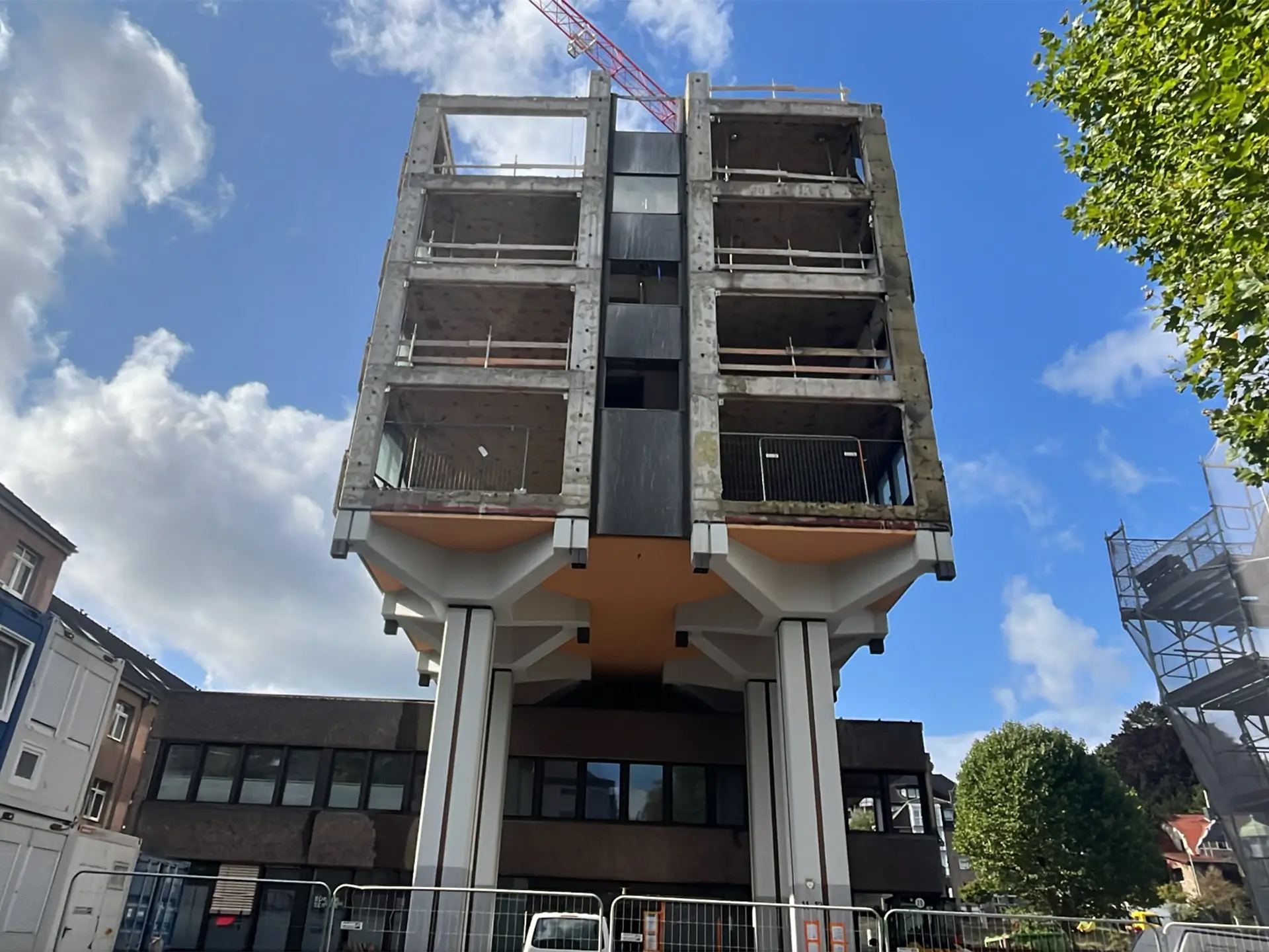 Freistehender Gebäudeteil des ehemaligen Verwaltungsgebäudes in Stolberg, auf Stelzen getragen und bereits teilweise entkernt, vor blauem Himmel.