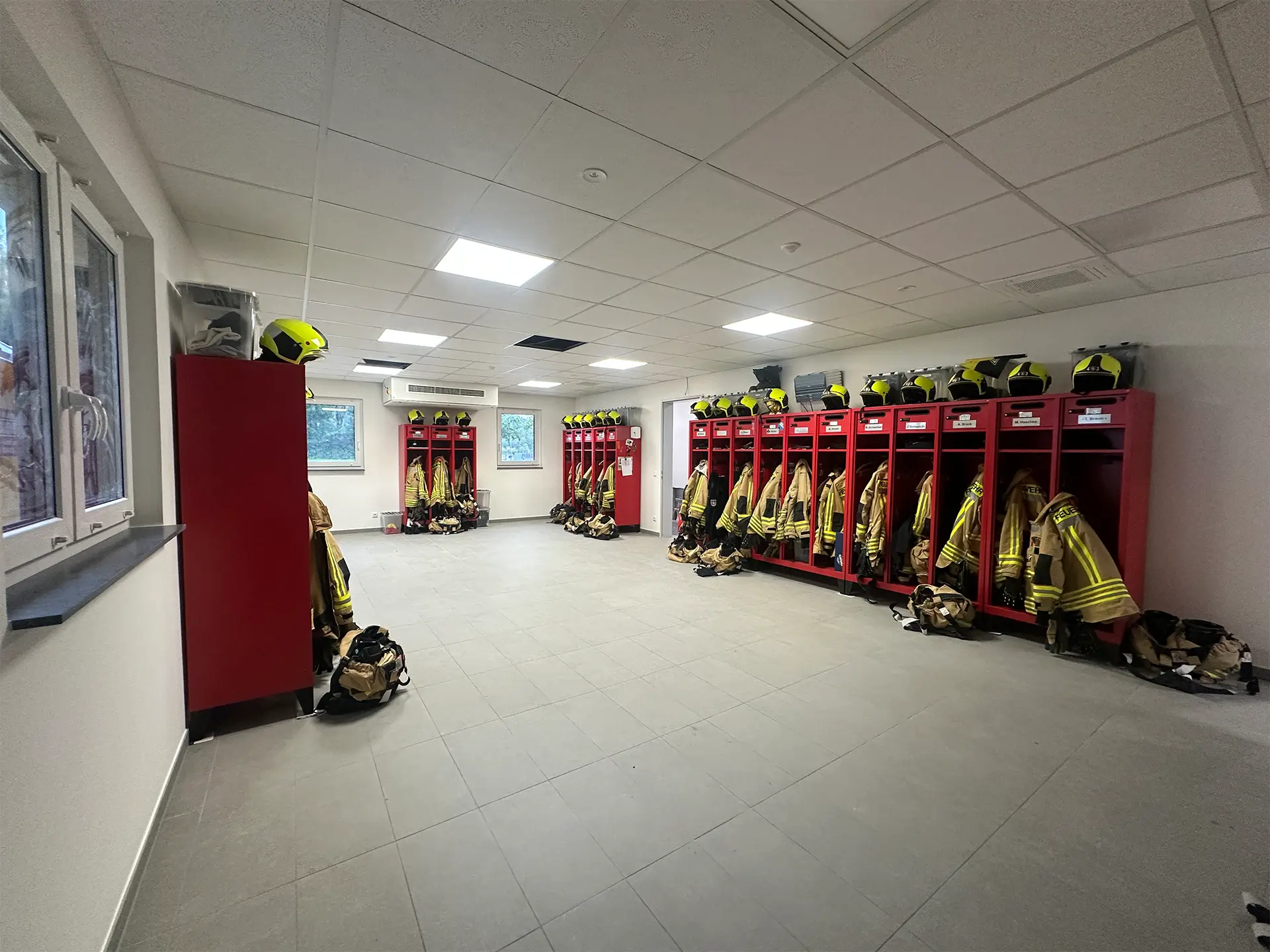 moderner Feuerwehr-Umkleideraum mit roten Spinden, Schutzkleidung und neuer technischer Ausstattung