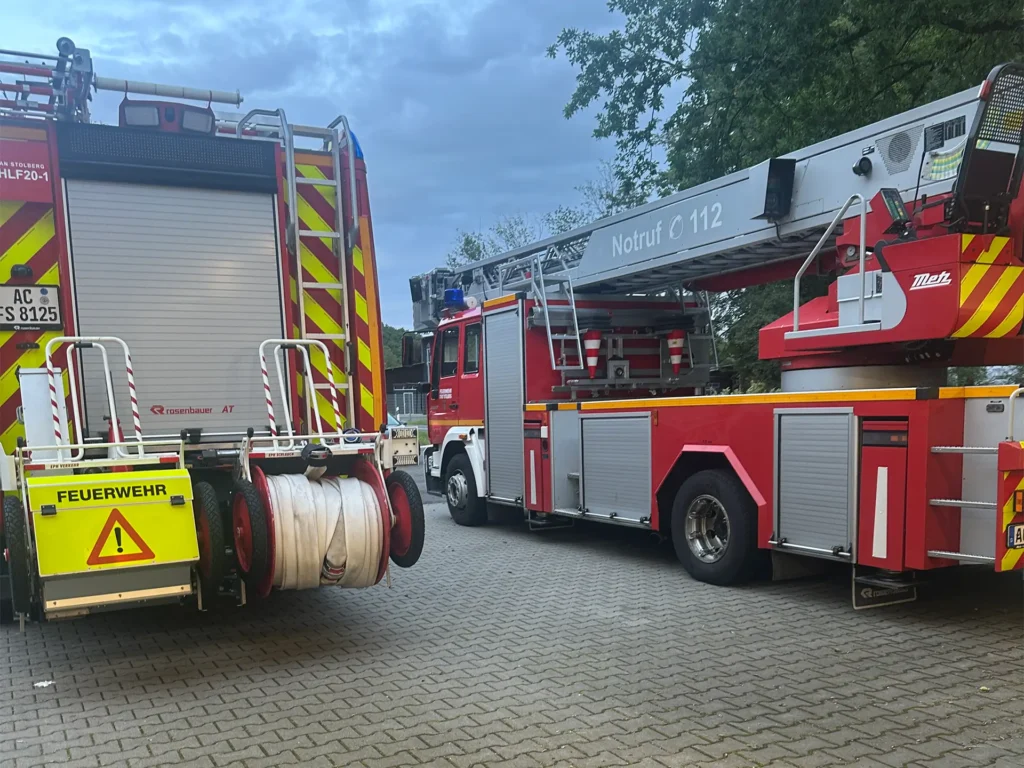 Moderne Löschfahrzeuge und Drehleiterfahrzeug mit Notrufnummer 112