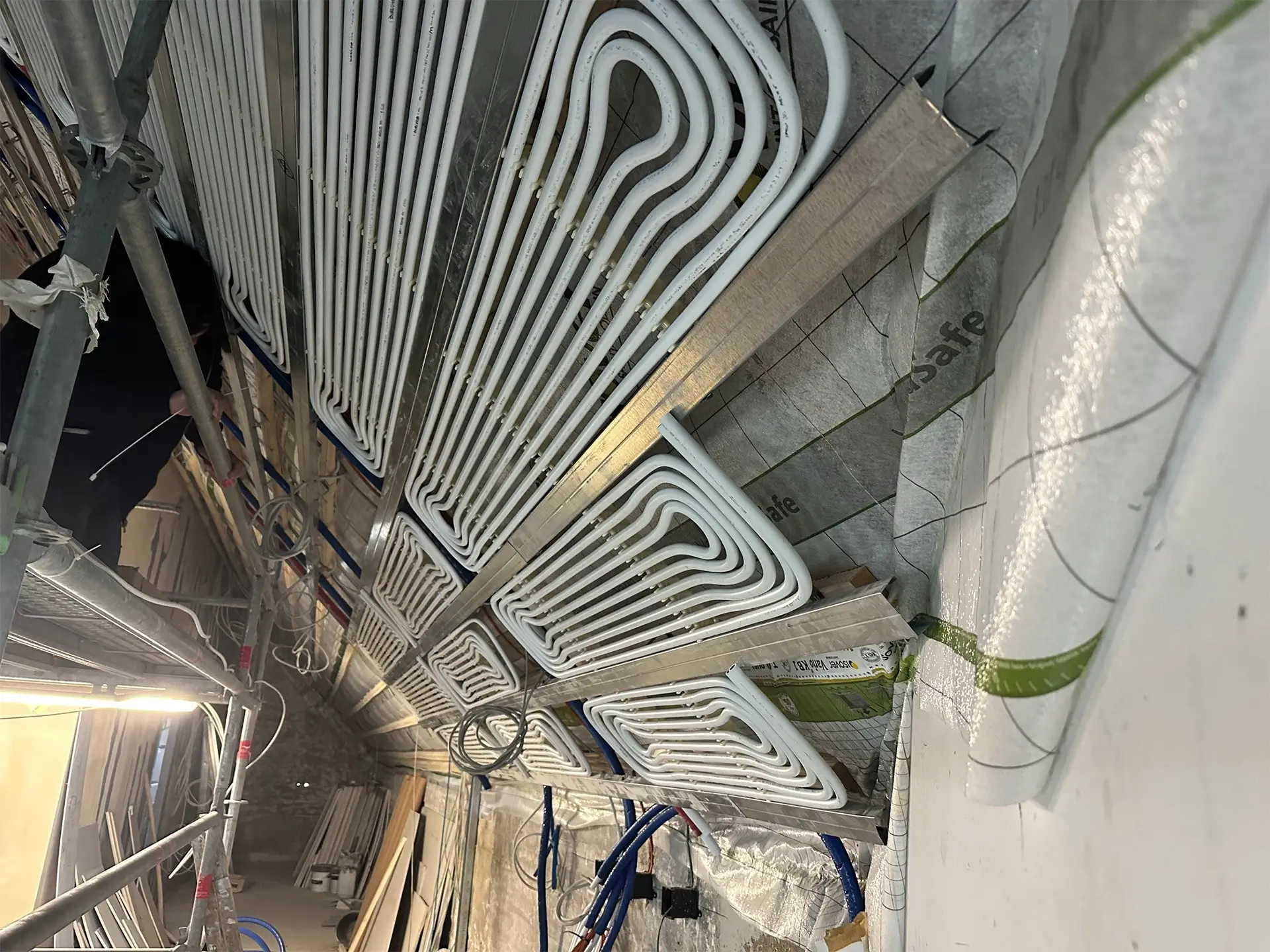 Montage von Heiz- und Kühldecken im Ratssaal: In Metallkassetten verlegte Rohrleitungen für ein strahlungsbasiertes Heiz- und Kühlsystem vor der finalen Deckenverkleidung.