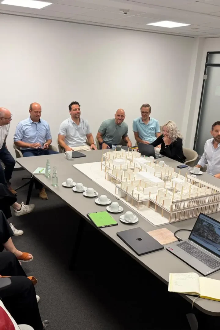 Teilnehmende eines Workshops diskutieren gemeinsam über das Modell des geplanten Rathausneubaus der Kupferstadt Stolberg in einem Besprechungsraum.